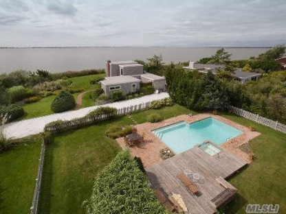 You must see this 4 bedroom, 3 bath modern. This waterfront home boasts the most spectacular sunset bay views, to be seen anywhere in the Hamptons. There is a master suite and bath, with a large private sundeck upstairs. 3 guest bedrooms, 3 baths. There is a bayfront livingroom and dining area with fireplace. The Gunite heated pool features a hot tub spa with waterfall, and is surrounded by a huge brick patio. This home has been completely updated and includes an all granite custom chef's kitchen, new roof, new heating and AC system, and more. All this on a totally private landscaped acre with plenty of room to expand on the second floor. Our Exclusive.