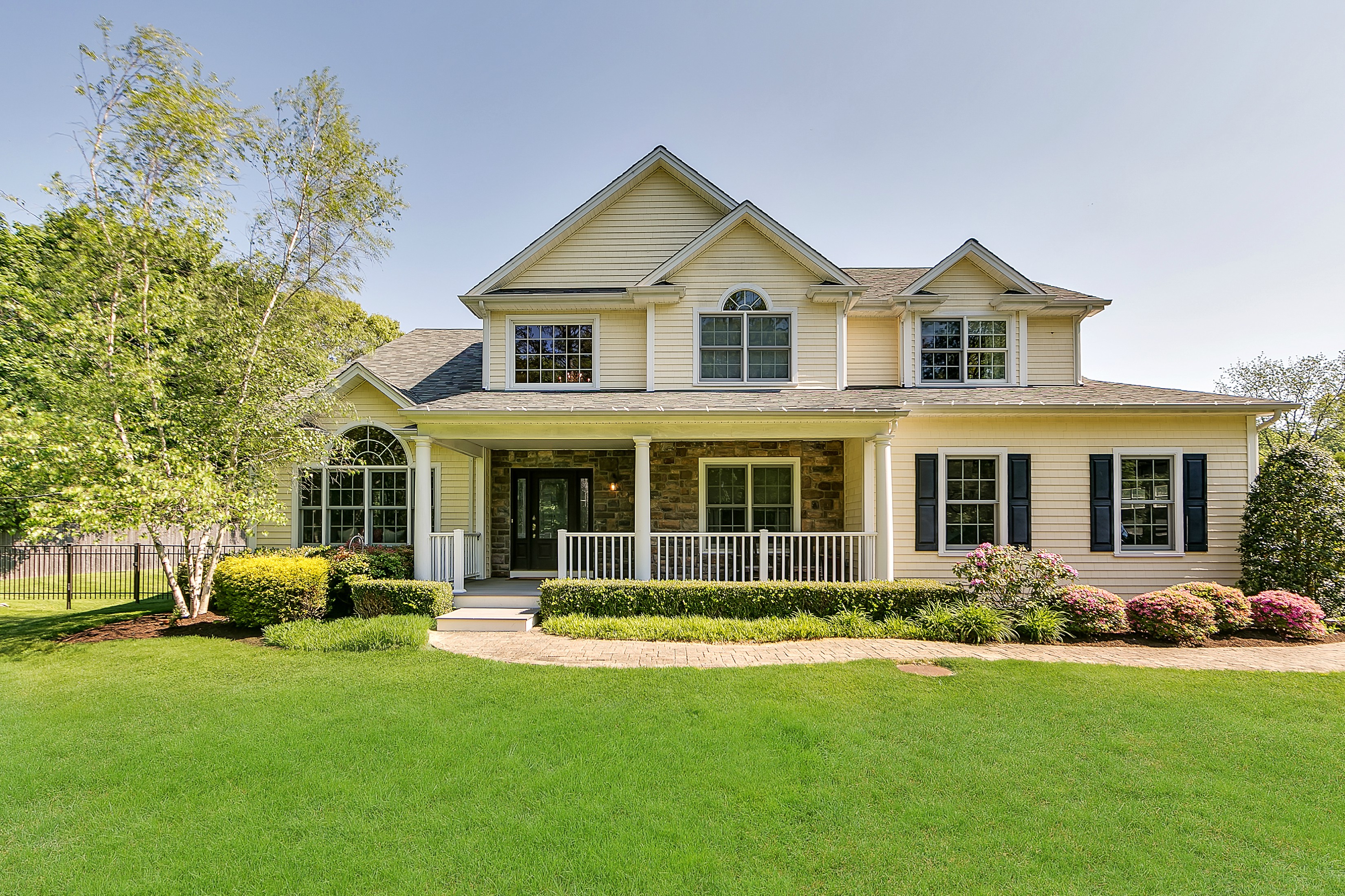 HUNTINGTON. Enjoy a sense of serenity and country living in this 2007, like-new, 4,500-square-foot home, featuring five bedrooms and three baths. Combining several architectural styles, including a large rocking-chair porch and Palladian windows, this two-story home offers a charming “farm house” persona and is surrounded by well over an acre of beautifully-landscaped, level, sweeping lawns, estate fencing, playground, hot tub, and glistening inground, heated saltwater pool with automatic cover and travertine stone surround. Approached off a private drive in Huntington, about two miles from the train station and from the town’s delightful shopping district, it is convenient to village dining, golf, yacht clubs, harbor, and beaches. Visitors are welcomed into a sunny two-story foyer with fielded-panel wainscoting, guest double closet, graceful staircase, and gleaming hardwood floors that flow throughout the home. To its left, a bright and airy living room boasts a large Palladian window reaching toward the high vaulted ceiling. Custom-paint stain-trimmed hardwood floors and wainscoting extend through a large doorway, with custom moldings, into the gracious formal dining room that overlooks the side and rear property. The adjoining eat-in kitchen is a gourmet cook’s dream featuring ample, granite-topped cherry cabinetry, center island, planning center, high-end stainless steel gas cooktop and hood, dishwasher, wall double-oven, and side-by-side refrigerator with in-door filtered ice and water. Hardwood floors flow into the sunny breakfast area, with bay window overlooking the rear property, and into the family room that features a gas fireplace, windows, and French sliding doors opening to the rear stone patio. This summer retreat is a perfect venue for conversation, sunbathing, al fresco dining and soaking in the hot tub. Also on the main level a study/bedroom, marble full bath, and mudroom with custom built-ins. On the second floor, a palatial master suite offer a spacious master bedroom with tray ceiling, custom closets, and an inviting gas fireplace with marble surround and overmantle niche wired for television. The luxury master bath provides a modern-style built in bathtub, shower, vaulted, sky-lit ceiling, and Corian topped twin vanity. Three additional bedrooms share a large bath that includes a granite-topped twin vanity and large tub/shower with partial glass wall. The full, finished basement provides plenty of space for play or development into any number of uses. Providing ample space perfectly maintained to resemble brand new, this special home provides a perfect setting for enjoyable, year-round living and entertaining. 