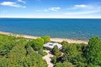 Serenity by the Sound. This beach house sits on over 2 acres, and is right on Long Island Sound. The home itself is a mid-century marvel with floor-to-ceiling glass walls that provide dazzling water views no matter where you are in the house. The spacious patio offers an impeccable entertainment space, and a private outdoor shower marries function with luxury for this waterfront oasis. A charming pergola replete with outdoor seating is ideal for enjoying the gorgeous panorama. The midcentury modern lines, elegant curves, and expansive windows make this home a true architectural treasure and the epitome of an idyllic retreat.