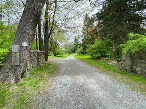 Stone walls welcome the gravel road to the home.