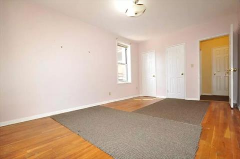 Large corner bedroom has hardwood floors.