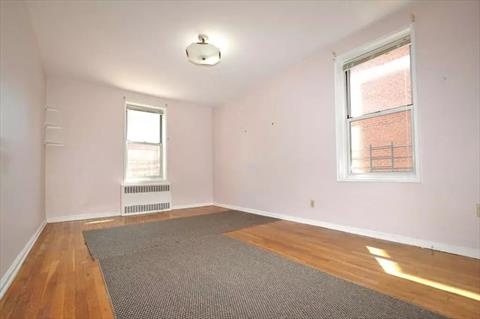 Large corner bedroom has hardwood floors.