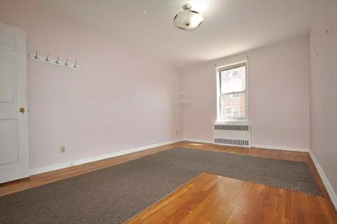 Large corner bedroom has hardwood floors.