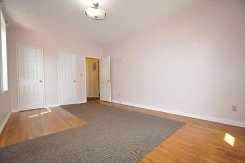 Large corner bedroom has hardwood floors.