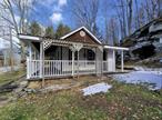 Come see this high efficiency, clean & cozy country home nestled in the hills of Sullivan County. Recent renovations make this 2 bedroom cottage really stand out. Step through the front door from the lovely wrap-around porch or enter through the sparkling kitchen equipped with energy saving appliances. The large stone fireplace in the living room anchors a rustic yet modern motif. The brand new bathroom, water heater, laundry hookups, & powerful ductless heating/AC unit are part of comprehensive updates along with new plumbing, wiring, & insulation. Some of the original hardwood has been rejuvenated while other areas were treated to all new flooring. A third door past the laundry area leads outside to a small shed & the impressive stone outcropping behind the home. To complete the thoughtful updates, a drainage system was installed at the foot of the ample driveway. This modern, efficient gem is waiting for you to fill it with love & make some memories. May also be used as an investment property.