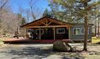 Country cottage in the lake community of Smallwood NY welcomes a new owner. Located on a semi-private lot with beautiful rock outcroppings this is a great place to escape,  for some solitude or for entertaining. Lot across the street is included in the sale to ensure privacy. Driving up you will first see the expansive covered deck, great for afternoon cocktails and bbq&rsquo;s, and relaxing under to enjoy rainy days, or ward off the sun. Once inside you enter an open floor plan with kitchen living room and dining area. Definitely a shabby chic feel, with an all white feel, weathered wood and distressed paint seen in the kitchen cabinets and barn door. Although the home is heated by electric baseboard, there is a wood stove to enhance the country vibe. Main bathroom is updated and there is also a full bath in the primary bedroom. There is also an additional bedroom. If you need more sleeping area there us also an additional living room that is available. This room is adorned by windows and overlooks the yard with firepit. Smallwood community has many amenities, lake access to non motor boat lake, dog park, hiking trails, tennis courts, and even has a waterfall. Also has community building with pool. All at your disposable at a very reasonable yearly fee. Close to Bethel Performing Arts Center and lake side dining. Home was easily rented out as Airbnb in the past. Taxes includes both lots.