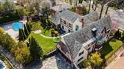 Featured in the Wall Street Journal, Daily Mail and NY Post. This historic English Tudor exudes elegance and has been meticulously designed to reflect a commitment to quality and excellence! 4 years were spent renovating the circa 1930s. Spanning 7, 987 sq. ft. with 4 bedrooms and 4.5 baths over 4 full floors of living space (including a finished bi-level attic and basement) 84-01 Midland Parkway is designed for living on a grand scale. As you enter the home via the spectacular rotunda you&rsquo;ll be amazed by the intricate design of the custom wrought-metal banister and chandelier, the expertly hand-painted domed ceiling with cove lighting and Versace-patterned key moldings, along with skillfully hand-painted murals. The elaborate crown moldings are a true work of art and are a signature component of every room. The home&rsquo;s ballroom is a sophisticated space with a combination of a grand marble fireplace, and crystal lighting. Beyond the pillars, you&rsquo;ll find a bright sunroom lined with oversized windows. With its expansive size, the formal dining room provides ample space for hosting lavish or intimate gatherings and is crowned with a striking Murano glass chandelier. The eat-in island kitchen offers the same attention to detail with solid wood cabinets, intricately carved moldings and granite countertops. There&rsquo;s a full suite of paneled high-end appliances and a wine cabinet. The room boasts excellent flow thanks to two entrances from opposite ends of the space. The half bath on the main floor is complete with unexpected finishing touches including a gold-plated sink. Retreat into the elegance of the library or the cigar room, each wrapped in rich mahogany. Enjoy the sun-drenched library with a balcony and decorative fireplace. Unwind in the cigar room equipped with cigar humidor and wine temperature-adjusted cabinet, along with wood-burning fireplace. Four sizeable bedrooms each have an ensuite bathroom, with a stand-up shower with tub. As you enter the main bedroom your eyes are immediately drawn upward to the stunning cove ceiling with plasterwork detail. The adjacent bath offers all the comforts with a Jacuzzi, stand-up shower, bidet, and a makeup room. There is a convenient laundry room on this level. Dual mahogany staircases serve to connect the levels of the house from two locations. A circular mahogany staircase leads to a bi-level attic with an open loft space, two additional bedrooms, and a full bathroom. The lower level of the house offers a wealth of amenities, a gym, sauna room with shower, and massage room with a wood-burning fireplace. Relax in the sizeable family room with a wood-burning fireplace tiled with terrazzo stone, equipped with surround sound, and a billiards room. A special treat is a fully equipped woodwork room. The property extends from Midland Parkway at the front of the property, to Radnor Road at the back, where the entrance to the heated 3-car attached garage can be found. Within the home&rsquo;s spacious and lushly landscaped 19, 843 acre lot, is a newly-refinished in-ground pool surrounded by a stone patio.