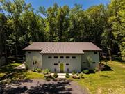 Nestled on 9.1 acres of private, sought-after land, yet just a mile from the vibrant town of New Paltz, this ultra-modern home offers an unparalleled living experience. A 1, 200-foot driveway ushers you into a world of tranquility, where contemporary design meets natural beauty in perfect harmony. The single-pitch, standing-seam roof and sleek metal siding seamlessly blend with the lush surroundings, offering a striking first impression. Step inside to discover the home&rsquo;s unique character, highlighted by its insulated concrete construction and two polished concrete walls that create a bold, custom aesthetic. At the heart of the home lies a gourmet kitchen designed for culinary enthusiasts, featuring top-of-the-line appliances, granite countertops, and a spacious peninsula bar perfect for cooking and entertaining. The kitchen&rsquo;s open design extends to the second floor, showcasing a dramatic 24-foot wall with eight-foot windows that flood the space with natural light and offer breathtaking views of the surrounding woods. The first-floor primary suite is a luxurious retreat, complete with an ensuite bath featuring a deep soaking tub and a separate tiled shower for a spa-like experience. Each additional bedroom also boasts its own private ensuite bath, ensuring convenience and privacy for all. Outside, a wrap-around patio invites you to dine al fresco, relax, or simply take in the serene beauty of the property. A hot tub provides the ultimate spot for unwinding while soaking in the starry night sky or the lush, green landscape. This home isn&rsquo;t just about beauty it&rsquo;s designed with energy efficiency in mind, featuring radiant heat within the polished concrete floors for year-round warmth and comfort. Combining innovative design, modern amenities, and energy-efficient living, this architectural gem offers a contemporary lifestyle infused with the tranquility of nature. Just a mile from New Paltz, this home is an exceptional opportunity for those seeking a sophisticated, serene escape.