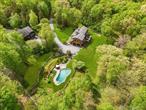 Just 90 miles north of NYC, this stunning Hudson Valley property offers the ultimate live, work, play lifestyle. Nestled on 4.08 private acres, this custom-built log home captures the vibrant essence of the area, known for its booming art and music scene, farm-to-table eateries, outdoor adventures, and local wineries. Generating over $80, 000 in VRBO rental income in 2022, this turnkey estate is both luxurious and versatile. Down a picturesque driveway, surrounded by mature trees and blooming perennials, you&rsquo;ll find a 20â€™ x 40â€™ heated saline pool set in natural stone landscaping, a two-car garage with radiant heat and an EV charging port, and a massive two-story carriage house with a 3, 000 SF workshop. This upstate retreat perfectly embodies the live, work, play ethos. The rocking chair front porch leads to a handcrafted wood door, opening to a sunlit open-concept layout with exquisite details. The gourmet chef&rsquo;s kitchen boasts custom wood cabinets, Brazilian Uba Tuba granite counters, stainless appliances, and a spacious eat-in area, plus a 20x40 rear deck for al fresco dining. The ground-floor primary suite features an en-suite bath with a soaking tub, separate shower, and a large walk-in closet. The main level also includes wide plank hardwood floors, a living room with a stone fireplace, a half bath, a laundry room, and a butlerâ€™s pantry with a side-by-side stainless refrigerator/freezer. Upstairs, find three bedrooms, a full bath with a walk-in shower, a lounge/gaming area, and a custom family room/theater. Above the garage, separate guest quarters with two bedrooms, a common area, and a private bath provide additional space. The downstairs family room is a bonus space with a full bath, stand-up shower, and cedar sauna. Outdoor highlights include the natural stone landscaped pool area with a jumping stone and fire pit, and a detached carriage house with a surround sound system, parking, office with a half bath, and camper docking station. No matter how you spend your time here, this Hudson Valley gem offers endless possibilities for living, working, and playing in style. Additional Information: Amenities:Guest Quarters, Storage, ParkingFeatures:1 Car Detached, 2 Car Attached,