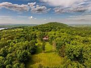 Unsurpassed opportunity. Private family compound or pampering hospitality venue minutes from downtown Hudson!. Exquisite estate on 100 park-like acres with historic 6000SF manor house, 2100SF guest cottage and a cavernous 7, 000 SF Barn structure. History shows that the famed Hudson River artist Frederic Church participated in the siting and construction of this impressive house which is a located near his own renowned masterpiece, Olana. The manor is an elegant, three story, stick style home with Catskill Mountain views and sunsets right out of the paintings themselves . Lovingly restored, the house has 7-Bedrooms (all with ensuite baths), spacious wrap around porch, floor to ceiling double front doors, impressive foyer with sweeping mahogany staircase, soaring 15 foot ceilings, hardwood floors and a swoon-worthy dining room off the foyer with a carved working fireplace, floor to ceiling windows, the largest is a Western facing mammoth plate glass window offering a masterpiece Catskill Mountain view. The kitchen is large and features a preserved red brick fireplace with woodbox. The first floor has high ceiling parlor rooms for libraries, music or winter gathering by a fire. There is a primary bedroom on the first floor wing with spa-worthy ensuite bathroom. This recently added wing provides an ADA compliant entrance off of a deck with a ramp. The storybook Guest Cottage, constructed in 2002, is ideal for caretaker or additional house guests, features a large open floor plan with 2-bedrooms each one with an ensuite baths. The easily customizable Pole Barn building offers endless opportunities as an entertainment venue, restaurant, private sports arena, gymnasium, art gallery space, vintage car collection display, etc. The long, winding entrance drive uphill leads to captivating walking trails, protected woodlands, picturesque stone walls and sweeping views in all directions. A mere two hours from New York City and minutes from the creative and entrepreneurial excitement of Hudson, New York and the Amtrak station. If you&rsquo;re in need of a private compound with room to grow that is steeped in the rich history of the Hudson Valley, this is a gem. It&rsquo;s reputation as a boutique hotel and wedding hospitality venues make it a strong choice to further grow a branded experience . And, the 100-acre parcel provides the perfect canvas for added expansion and development near Hudson!