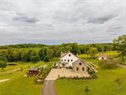 TURNKEY IN MILLBROOK: A discreet tree-lined drive with expansive views of two ponds and rolling hills leads to this stunning modern farmhouse. Sitting on 10 exquisitely manicured acres with an in-ground pool and spa, 3585 Route 82 is the perfect weekend retreat or full-time home. Flanked by gardens reminiscent of the English countryside, tasteful finishes, custom millwork, generous proportions, and breathtaking views complete the package. An elegant entrance leads to a gracious foyer and a grand living room beyond it with a wood burning fireplace overlooking the beautiful view. Slide open the doors to the pool area for indoor/outdoor living at its peak. The chef&rsquo;s kitchen is equipped with a 4-door Samsung refrigerator, a Bertazzoni free-standing vintage range, a microwave, multi-wall and steam ovens, and a warming drawer. An integrated hood is set against a hand-made Zellige tile backsplash. The dining area features a wall of custom cabinets and a bar by renowned English cabinet maker deVol, and creates a natural separation for the ample office/den and fitness room at the rear of the house. The first-floor luxurious primary suite wing adjacent to the great room enjoys amazing westerly sunset views over the foothills of the Berkshires. The primary bedroom features a fireplace, walk-in closets, and a large bathroom with a walk-in shower, deep freestanding spa tub, inlaid marble floors and a state-of-the-art Toto toilet. The chic deVol-designed laundry room is also located on the first floor, as well as a jewel box powder room. The 2-car garage is accessed through the mudroom adjacent to the garage entrance. The gym and office with its cozy fireplace complete the 1st floor. There are 3 generous ensuite bedrooms upstairs including a luxurious 2nd primary, each with walk-in closets and perfectly framed vistas. The 2nd level boasts a cozy media room, which doubles as a 5th bedroom with a full bathroom adjacent to it. The pool area features a built-in outdoor kitchen with a bbq and pizza oven and bluestone patio. A French lavender garden leads to a second outdoor lounge. The studio building replete with a full kitchen and bath provides additional guest, office, or artist&rsquo;s studio space. As if that weren&rsquo;t enough, the full, dry basement with a temperature-controlled wine cellar, and the full floor attic with high ceilings are your ultimate recreation spaces. This turn-key Millbrook gem, protected by majestic farmland, is perfectly located a stone&rsquo;s throw from the village.