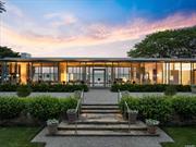 Discover the Glass House. An architectural marvel on Fishers Island, designed by Tom Phifer to blend seamlessly with its lush surroundings. This steel-and-glass home, with unobstructed views of Fishers Island Sound, stands on the site of a former colonial home. The garden, designed by Morgan Wheelock and enhanced by Thomas Armstrong, features vibrant Japanese irises and 150, 000 daffodils. Phifer&rsquo;s design emphasizes transparency, allowing the house to blend into the landscape. The home&rsquo;s steel frame complements the maritime blues and grays of the Sound. A water feature flows through the house, enhancing the connection between the structure and the garden. The primary bedroom, dappled with light, offers views of the meticulously manicured garden. Inside, the house is a masterpiece of minimalism, with walls that don&rsquo;t touch the exterior, creating uninterrupted views. The exterior canopy of aluminum tubes blocks direct sunlight, ensuring comfort and beautiful soft light. The interior features six skylights and minimal doors, emphasizing the peaceful expanse of the space. This property, a sanctuary of art, architecture, and nature, offers a serene retreat on exclusive Fishers Island, accessible only by ferry, boat, or plane. Experience unparalleled living in this harmonious blend of design and natural beauty.