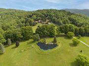 JUST LISTED in the CATSKILLS: Encompassing over 47 ACRES, 94 Overlook Drive is a truly luxurious estate comprised of a show-stopping main residence of 3 bedrooms, 4-1/2 bathrooms and over 3, 800sf, a primary 1, 256 sf 3-car heated garage, a 520 sf guest house/gym, a 400 sf cottage and two additional utility buildings/garages and home to a monument memorializing a Revolutionary War soldier (1764-1847). Designed to the specifications of owners Carol-Ann and Lou Bloise, architect Lee Friedman enhanced additions to this eclectic contemporary home set on 25 acres of pristine, private and manicured perfection, the property is replete with stone walls and rolling, verdant grounds in the Town of Andes. This rare parcel of preserved natural beauty is the epitome of Upstate New York, Catskill&rsquo;s living, and, just 2.45 hours northwest of New York City (amazing drive along the Hudson River). Striking, breath-taking, long-range MOUNTAIN VIEWS from practically every room. Entering through the 3-story tower, you&rsquo;ll find an open floor plan with walls of windows overlooking the grounds. Dining area with fireplace, updated eat-in-kitchen with new state of the art stainless-steel appliances and opens to a rear patio with outdoor grilling/eating space and abundant built-in seating. Numerous wooden walkways, decks and outdoor seating areas abound. There is a main level bedroom with spectacular full bath. Step down to the living room with fireplace or enjoy the library with fireplace and opens out to a deck overlooking the estate. Off the kitchen is a staircase down a stone-lined wall to a media center with fully stocked bar, dishwasher and refrigerator. Take advantage of the EuroCave temperature controlled 200-bottle wine cooler for entertaining. The primary ensuite bedroom upstairs includes a 6&rsquo;x6&rsquo; tiled shower and separate sitting area and an additional bedroom with that wow circular window offering unparalleled mountain views. Additional structures include a guesthouse/gym recently updated with siding and windows and features a curved wall bathroom, a steam shower and sauna. Most impressive are the grounds which include a koi pond with seating to enjoy the views, numerous manicured specialty gardens to explore, 2 additional garage utility buildings and a 400 sf 2-story cottage. Secreted away is a shooting range and the revolutionary war monument (Waterbury Cemetery) for Daniel Waterbury. Private, secluded, quiet rural area, minutes to amenities in Andes. An incredible opportunity awaits you.