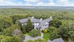 The Most Architecturally Remarkable Residence in Water Mill.  6+ Acres, 950 SF Infinity Pool, Movie Theater, and more. Available for the First Time Ever. Lively and luxurious, this stunning 6-bedroom, 8.5-bathroom masterpiece spans nearly 12, 000 square feet. Conceptual work was done by AD recognized designer Greg Jordan, while renowned interior designer Sasha Bikoff reimagined many of the home&rsquo;s individual rooms and spaces.  This exceptional property sits at the end of a long, wooded path with a remote-controlled entry gate for added privacy. A grand two-story house comes into view, featuring sand-blasted Cypress siding, simulated slate shingles, and an enchanting turret surrounded by lush landscaping and foliage. The grounds feature a quartzite stone patio, verdant lawn space, and a stunning infinity pool with serene countryside views. There is more than enough room for a tennis court, and the detached garage has an alarm system and can accommodate up to 5 cars.  Interiors of the home are spacious, colorful, and bright. English brown oak floors complement custom built-ins, exposed beams, crown molding, and bay windows. The HVAC system includes environmentally friendly coolant, 13 remote-controlled temperature zones, 240 gallons of indirect hot water heaters, and 4 hot water boilers that produce 1 million BTUs of heat. Power comes from 10 sub-panels with 800 Amps supply, and all areas are wired with Fiber and Cat-5/6 cabling. The home has four staircases in total-two leading to the upper-level wings and two leading to the lower-level wings.  On the FIRST LEVEL, residents are greeted by a grand foyer and spiral staircase with a gleaming chandelier and soaring 32-foot ceilings. Beyond the foyer is a sun-splashed great room with 30-foot ceilings, multiple access points to the outside areas, and a double-sided wood-burning fireplace with a floor-to-ceiling stone surround that connects to a tranquil library. The formal dining room has a fireplace and swinging doors leading to a windowed butler&rsquo;s pantry perfect for prep work and storage. The kitchen has its own fireplace, two sinks, and high-end stainless steel appliances. There is also a quiet bedroom wing with a windowed kitchenette and a pair of en-suite bedrooms with access to a private deck. The SECOND LEVEL has three bedrooms with en-suite bathrooms, walk-in closets, and private outdoor balconies. The primary suite occupies its own wing and has his-and-hers offices and closets and a private balcony with views stretching to the ocean on a clear day. There is also a windowed kitchenette perfect for enjoying morning or evening beverages and snacks.  On the LOWER LEVEL, a central hall connects two separate wings. An en-suite bedroom, laundry room, mudroom, full bathroom, and private gym occupy one wing, while the other features a dazzling theater-style media room, game room, and cinema with playful design features, a full bathroom, and access to the outdoors. Whimsical pendant lighting adorns a marble wet bar with a fridge, ice maker, and sink. A pool table anchors the space, and vivid seating and carpeting create a truly unique space. The cinema was optimized for sound by an acoustic designer.