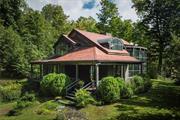 A long, winding, forested driveway weaves up into the hills to reveal this incredible custom home nestled into the trees. With nary a neighbor in sight, this peaceful property is an ideal retreat, offering absolute privacy. Dramatic steel beams fan out from an impressive two-story stone chimney leading to a curved floor-to-ceiling wall of windows. This unique design frames your mountain view and creates an exquisite backdrop for everyday living. The proportions are grand this is truly a home to marvel at but it still manages to feel warm and cozy. Oversized windows in every room fill each space with dappled sunlight and seamlessly integrate the surrounding natural beauty into the home. The first level is open and spacious with a huge living, dining, and kitchen area, a primary suite, laundry, and serene screened-in porch that is perfect for morning coffee with the birds. Upstairs you will find two more bedrooms and baths one featuring a Hinoki soaking tub. The views from this level are even more spectacular! The expansive property spans more than 46 acres of woods to wander enveloping the home within exceptionally peaceful natural surroundings. While the property itself is the epitome of privacy, Callicoon Center is central to so many great destination towns, with Callicoon, Livingston Manor, Roscoe, North Branch, and Jeffersonville only 10-20 mins away. A myriad of fine and fun dining can be found in the area starting right down the road at Conover Club at Callicoon Hills, and there are dozens of amazing local businesses to support! This area is famous for its sweeping rural beauty and fly fishing, in addition to tons of hiking, swimming, kayak/canoeing, and more. Two hours to the GWB in NYC.