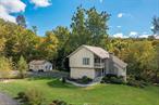 Perched on 3 wooded acres high above a natural stream, this 4-bedroom 3.5 bath Contemporary offers more than meets the eye. Natural landscaping sweeps down the drive, guiding visitors to a fresh stone path leading to the front door. The entry features a cathedral ceiling featuring a charming wood stove, set-off by large windows, soaring ceilings, hardwood floors, and a floor to ceiling stone fireplace. Passing the large hall closet, you enter a beautifully renovated kitchen with stainless steel appliances, hardwood floors and a large open concept Dining Room. The Kitchen and Dining Room offer large windows and a glass door opening onto an expansive wrap-around back deck overlooking nature at its finest, with a serene view of your ravine, the sound of running water, and abundant birds and wildlife. Main floor amentities also include a powder room, laundry/ mud room and large 2 car garage. On the second floor you will find two sunny bedrooms with sliding glass doors opening to their own balcony, a large hall bath and a private office. Further down the hall, a large Primary suite awaits, featuring hardwood floors, large windows, a sliding glass door to a private deck, walk-in closet and full bath. The lower level of the home features a sun-filled additional large living room/ office/ gym space with French Doors opening onto a private patio surrounded by a lush garden. This level also includes an ample fourth bedroom, a large full bath with walk-in glass door shower, and access to a utility space with secure double steel doors opening out to the back yard. In addition to its natural beauty, this meticulously cared-for home offers many luxury amenities, including: a 16x24 pole barn with electric service, water access and a mini split for heat and air; a whole house generator; water filtration system; a new roof; a 72 GPM continuous flow well pump; epoxy garage floor; central air and fresh paint inside and out.