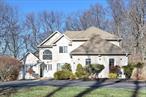 This custom-built Colonial home, crafted by a premier Rockland builder, offers exceptional quality and timeless appeal. Situated on a beautifully landscaped property with a circular driveway, the home greets you with a two-story entryway and an abundance of natural light from the large Pella windows situated throughout. The first floor features newly stained hardwood floors, recessed lighting, and an oversized Primary suite with a spacious walk-in closet. The master bath includes a separate tub and shower for added comfort. Freshly painted, the home boasts a generous living room with a wood-burning fireplace, and four-panel glass doors leading to a stunning patio and backyard. The formal dining room is perfect for entertaining, and the eat-in kitchen is equipped with new stone countertops, stainless steel appliances, and updated plumbing fixtures. The powder room has also been upgraded with new fixtures. The upper level offers a second Primary bedroom with an ensuite bath, brand-new pristine hardwood floors, and renovated bathrooms with modern vanities, fixtures, and toilets. It also includes a family room, three additional bedrooms, and two full bathrooms. A cozy deck with stairs leading down to the side yard adds charm to the space. The partially finished walk-out basement is extremely spacious and provides plenty of potential, featuring large windows, plumbing fixtures for a future bathroom, cedar closets, and laundry room. The two car garage has been rewired to accommodate electric vehicle charging. This home is built to last, with engineered wood beams, copper pipes, five zones of heat, and two-zone A/C.