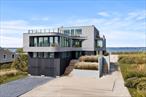 Welcome to Curving Dunes, a stunning Hamptons retreat built to perfection and expertly designed by First Dunes in collaboration with The Up Studio. This 6, 300 sq ft masterpiece spans three floors, offering seven bedrooms, seven bathrooms, and two powder rooms, all designed to elevate your beach living experience. Step into the grand foyer, where serene, neutral tones reflect the surrounding Hamptons beauty. The open-concept layout flows effortlessly from the living and dining areas to a chef&rsquo;s kitchen, equipped with top-of-the-line Gaggenau appliances and a spacious dining island-perfect for hosting any occasion. The living room opens up to your private outdoor haven, featuring an expansive deck with a heated infinity pool and integrated spa, all overlooking panoramic bay views. A separate guest residence offers privacy and flexibility, doubling as a home office or wellness suite with a sauna, cold plunge, experience shower, and yoga studio. The second floor houses the primary suite and two additional bedrooms, each with its own ensuite. The primary bathroom features a luxurious steam shower, soaking tub, and a private balcony with stunning bay views. Ascend via the unique transparent pneumatic elevator to the third floor, where two more ensuite bedrooms, a loft with a chic wet bar, and an expansive rooftop deck offer 360-degree views of the ocean and bay-perfect for savoring sunsets and sunrises. The meticulously landscaped grounds lead to a two-car garage with additional storage space. Enjoy exclusive access to Moriches Bay and the Atlantic Ocean, inviting endless Hamptons adventures. Welcome to Curving Dunes, where every detail reflects unmatched craftsmanship and elegance.