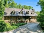 Located in the heart of the Snedens Landing Historic District, this original 1938 home has been thoughtfully renovated to enhance its timeless character and bucolic charm. The property retains its original stone facade and slate roof, while modern touches, including a mid-century style extension, have brought space and light to the residence. The highlight of the home is a bright glass room that is bathed in natural light. From here, glass doors open to a spacious brick patio covered by a trellis draped in mature kiwi vines, creating a serene outdoor space for a shaded al fresco lunch or drinks. The patio overlooks a free-form in-ground pool, which is completely fenced, the contours softened by clematis and climbing hydrangea. The surrounding cottage style gardens are planted with a range of mature specimen trees and a wild profusion of perennial plantings. Drifts of narcissi, grape hyacinth and daffodils surround the gardens in earlyspring, giving way to peonies and allium in May. There is a raised bed set up for a kitchen vegetable and herb garden. On the edge of the property there is a hand-built treehouse and beyond a fenced area originally used for chickens and other pets. Inside, the home offers an open country kitchen, complete with exposed stone walls and cork flooring. There is a Viking stove/oven and a classic Sub-Zero refrigerator. The kitchen seamlessly flows into a spacious living room with a Russian oak floor featuring a wood-burning fireplace, making it a perfect spot for cozy gatherings. The adjacent dining area is ideal for enjoying casual meals with family and friends. The first floor also includes a small bedroom with a full bath, in addition to a den that can flexibly serve as an office or an additional bedroom, with an adjacent half bath.Progressing to the second floor, a wide landing leads to the primary bedroom with a very generous adjacent full bathroom. A second double bedroom shares this floor, along with another full bath. On the edge of the property is a freestanding garage with a large upstairs studio with a wood burning stove and walk in closet. Currently configured as a work from home office suite there is a bathroom/shower on the lower level making it an ideal separate apartment for a nanny or overnight guests. This property is steeped in history, with its location in the Historic District offering a unique connection to the past, particularly the Revolutionary War era. Quaintly described in Historic Houses of Palisades as â€œThe House That Jack Builtâ€, the architect Wallace Heath has added a creative touch to this home, making it an appealing haven for artists. Former residents include Pinchas Zuckerman and Tuesday Weld. The home is a short walk from the Snedens Landing Tennis Association, the Palisades Free Library, and local favorite, The Filling Station restaurant. The location is excellent for hiking and biking as this private road ends in a trail that leads to the village of Piermont and beyond. Snedens Landing is conveniently located just a 12 mile drive from the George Washington Bridge or a 10-minute drive from the Mario Cuomo Bridge, making it an excellent choice for those who need easy access to the city while enjoying the tranquility of a historic and artistic retreat.