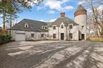 Step into a timeless retreat where elegance meets tranquility in this one-of-a-kind gated estate in the heart of Muttontown. Spanning two professionally manicured acres, the property features four distinct structures surrounded by lush English gardens, towering trees, and romantic French-inspired meditation spaces. The main residence, reminiscent of a mini-castle, welcomes you with a grand living room, a dining room with a fireplace, and rich wood floors. A brand-new gourmet kitchen flows seamlessly into a cozy den with a fireplace and a charming dining foyer. All main entertaining spaces open to the beautifully landscaped grounds, inviting in natural light. The second floor boasts a lavish new primary suite with a bar, plus two additional bedrooms and a full bath. The separate cottage offers a versatile layout, with a two-room office and kitchen on the main floor, while the second level features two bedrooms and a bath. Outdoors, a spectacular saltwater pool awaits, accompanied by a stunning 1, 500 sq. ft. pool house, complete with a spacious entertaining area, full kitchen, bath, and laundry. A detached three-car garage, along with an additional one-car garage in the main house, ensures ample parking. This exquisite gated property also benefits from Muttontown police surveillance, low taxes, and a prime location near top-rated schools, shopping, golf courses, and tennis facilities. A rare and exceptional find!