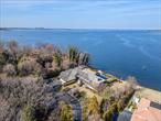 This contemporary waterfront residence in the sought-after Village of Kings Point offers an unparalleled blend of modern luxury and natural beauty. Situated on over an acre of prime waterfront property, the home features expansive floor-to-ceiling windows, multiple balconies, and a roof deck, all designed to maximize the breathtaking water views. The interior boasts a spacious living room with a fireplace, a formal dining room, a comfortable den, and a gourmet eat-in kitchen equipped with state-of-the-art appliances. The property includes five bedrooms and five and a half bathrooms. The primary suite is a luxurious retreat, featuring separate his and hers bathrooms and a private sitting room with breathtaking waterviews. A fully finished basement offers a versatile space, including a playroom and a gym, 2 guest bedrooms with baths. This property exemplifies modern waterfront living in Kings Point, combining architectural excellence with luxurious amenities.