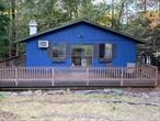 Privately set Ranch home on a dead end lane. Ideal starter home or Your Weekend getaway. This Mid Century modern home is surrounded by woods which allows for quiet seclusion yet convenient to restaurants, shopping, pharmacy and a beautiful Town park. The home features 2 bedrooms and 1 bath, hardwood floors with an open dining/kitchen and living room with fireplace overlooking a wrap around deck well maintained with plenty of room for gathering of friends or solitude. There is an unfinished basement which has the potential of being finished into two additional bedrooms and one bath subject to obtaining proper permits. This home is in an HOA called Emerald Green which has New pools, tennis courts, pickleball courts, clubhouse, boating, fishing, swimming etc.  Annual dues are $1746 can be paid monthly or yearly. There is a special assessment yearly of $725 until 2033. Buyer to pay $1761 transfer fee to Emerald Green at closing.