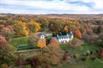 Set in the hills above Millbrook, West Meadow is encircled as far as the eye can see by endless, heart-stopping views of the entire Hudson Valley. The house and pool sit on a beautifully landscaped plateau above a sloping lawn that gives way to a prolific cutting garden, rose beds, tennis court wrapped in wisteria vines, and groomed meadows. A fruit orchard and abundant vegetable garden enhance the pastoral beauty while providing a measure of sustainability. The architect Pietro Cicognani designed a home that harmoniously balances details of comfort, beauty, modernity, and history. West Meadow feels as if itâ€™s been in place for centuries. The spacious great room boasts two 18th century stone fireplaces and floors of limestone tile imported from France. Fresh air and light pour in through six custom French doors facing both east and west. The library opens to a long covered porch and one of many stunning views. A central gathering place for friends and loved ones, the kitchen is warmed by a fireplace with pizza oven. In the summer, a wall of floor-to-ceiling windows and doors opens to fragrant gardens, thyme- and lavender-laced stone terraces, the uninterrupted panorama, and matchless sunsets. Upstairs, the primary suite features vaulted ceiling, large windows, and spacious accommodations for luxurious comfort and self-care, including steam shower and a soaking tub that has its very own view. On the bottom floor, a remarkable two thousand bottle wine cellar and tasting room offers something special for oenophiles and casual wine enthusiasts alike. Also on that level is built-in cedar storage, a full laundry, and a staff bedroom. A long, private drive leads through the natural habitat to every outdoor spot on the estate that has been designed for restful ease, comfort, and beauty. Discreetly set apart from the residence, outbuildings include a caretakerâ€™s home, a two-bedroom guest suite, heated greenhouse, four-stall equipment garage, full shop, office, chicken house, and run-in shed. There is ample room on the property for livestock or a stick and ball polo field. Surrounding the house, the columned porch allows for seating in sun or shade, and panoramic views for watching a storm approach, an eagle cavort, or the sun lower in the painted sky.