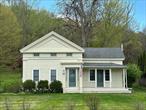 This quintessential classic Greek Revival/Eyebrow home, circa 1850, is located in a historic quiet country Hamlet. Ready to move in, it is in great condition, meticulously maintained, and has much to offer with lots of natural light and charming layout. Entrance hall leads to the living room on the right, bedroom to the left, and straight ahead, the original Greek Revival stair to the second floor. The spacious living room has a period mantle with a cozy woodstove insert and, at the rear, the newly renovated sunny eat-in kitchen has recently installed appliances, cabinets, and quartz countertops, with plenty of room for dining. The downstairs bedroom leads to a pleasant office space and to a full bath. The office also has a door to a delightful (unheated) garden tool shed which leads to the outside patio and gardens. Upstairs, are two bedrooms and a bathroom, plus a great studio or childrenâ€™s playroom in the finished attic wing. The almost one acre of property includes a vintage garage (with attractive roofline and shingles), stone patio, stone walls, mature trees, and paths bordered by beautiful perennial flowers and ferns. It backs up to woodlands and a monumental rock ridge on the adjacent property. Situated in the tiny historic Hamlet of Ancram, on the banks of the Roeliff Jansen Kill, where, according to Wikipedia, during the American Revolution, the Livingston Forge, powered by the Roe Jan, produced shot, cannonballs, and perhaps most importantly, the huge chain that was installed across the Hudson River at West Point as a defense against British ships going upriver. Today the vibrant Hamlet is home to Ancram Little Store (now a breakfast, lunch, and catering store), Simons General Store (now an artist studio), and Ancram Grange (now the Center for the Arts, an amazing performance venue). The home is centrally located between southern Berkshire mountains in Massachusetts, western Litchfield Hills in Connecticut, and, in New York State, northern Dutchess County and southern Columbia County. New York City is about two hours by car or train (Metro North via Wassaic or Amtrak via Hudson)
