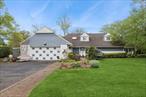 Light-filled Hewlett Harbor entertainerâ€™s dream on a private, nearly half-acre corner lot. Step into a marbled foyer leading to an open living/dining area with a wall of glass and a 15x16 den framed by 11 windows. The eat-in kitchen features granite countertops, stainless steel appliances, and large picture windows overlooking the lush backyard. A double-sided fireplace and wet bar create a warm, inviting atmosphere. The first-floor primary suite boasts vaulted ceilings, two walk-in closets, and a spa-like bath with jetted tub and bidet. A second bedroom/office and full bath complete the main level. Upstairs offers two more large bedrooms, a full bath, and access to an unfinished attic ready for expansion if desired. Two-car attached garage with direct kitchen access and a separate laundry room. Enjoy outdoor living on a secluded 1, 200 sq ft deck.