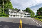 This is Bullis Hall, the circa 1800â€™s Greek Revival landmark in the picturesque and historic hamlet of Bangall in Stanford, NY. The Hudson Valley, Dutchess County property is situated with excellent street frontage on Hunns Lake Road just off Route 82. With over 6, 000 square feet, the building is ready for its next steward; a blank canvas for future use. Bangall is one of many hamlets in the town of Stanford, where the Dutchess and Columbia Railroads once rolled in from New York, servicing dairy farms and bringing summer vacationers to nearby Hunns Lake. J.H. and J.W. Bullis are the original names behind the building, who resided in the large colonial home across the street. The earliest documents of the building record a series of stores, including a tin shop, iron roofing fabrication, a post office and a modest hotel. The building evolved to become a gathering place for the community when a large elegant room was added circa 1900, that hosted musical performances, comedy shows, voting, and dinner meetings. Prominent town families such as John June and Thaddeus Knickerbocker were once tenants. Addison Berkey turned Bullis Hall into an opulent Bed and Breakfast years later, with an elegant smoking room, grand dining and credentialed chefs. Relais & Chateaux featured Bullis Hall in their well-known boutique hotel catalogue. You may enter Bullis Hall from the lovely stone walled, slate paved private terraced garden courtyard. On this main level is a large foyer with a fireplace which opens to the great room, also with a fireplace. Oversized windows, high ceilings are throughout, as well as detailed crown moldings. There are presently five â€œsuitesâ€ with baths; three suites are comprised of two generous rooms. Two suites have direct outdoor access. Another large room is used as a conference room. There is a beautiful long outdoor balcony overlooking the hamlet. The cozy, wood beamed lower level includes another wood paneled foyer. The street facing entrance is here with a newly poured cement walkway running the entire length outside. Back inside, another room with a fireplace leads to more space and then into the modern, custom-built gym, with new lighting and separate heat and A/C. Additionally, a half bath and more office/space is on this level. At the very top, third floor level, there is more living space with a kitchen and bath. New roof and gutters were installed in 2019, new well water pump 2023, exterior painting and new exterior decking were completed in 2020. Currently being used as office space. This is just two hours from New York and nearby Metro North and Amtrak. Nearby to shopping and dining towns of Millbrook, Sharon CT, Millerton, Rhinebeck and more. Welcome to the Hudson Valley!