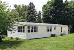 SPACIOUS, CHARMING, & AFFORDABLE! This 3 bedroom, 2 full bath, double wide manufactured home is move-in ready with tons of recent improvements! Situated on an oversized corner lot with a small running creek and lots of full grown trees providing plenty of privacy. Enter the front door through a wonderful enclosed screened in porch large enough to fit a dining table or to create a peaceful seating area to relax in. This home has a large sunny kitchen equipped with a new gas stove, refrigerator, and dishwasher; plus, abundant cabinetry, open shelving and fun design features that really make this kitchen shine! There is also a bonus laundry room with a washer and dryer included, and a full food pantry for extra storage; there is an eat-in-area featuring beautiful stained-glass windows and a corner shelf. This home features vinyl plank flooring throughout and an extra large livingroom with lots of windows that bring in tons of natural light. Off the living room there are two bedrooms and a full bathroom with a skylight window. On the other side of the home is a family room with a fantastic pass through/breakfast counter looking directly into the kitchen. The primary bedroom is located off the family room and has multiple custom features, such as; double doors leading into a large en-suite bathroom boasting a sunken soak bathtub with a fun wall feature, a stand up shower, a double sink vanity with mirror, and a nice size walk in closet. The lot also comes with a big storage shed that has been completely updated as well. The location of the mobile home park is PERFECT, and it has amazing views of gorgeous horse farms right at the entrance. It is located approximately 10 miles north of Rhinebeck (and the fairgrounds) and about 10 minutes from the Town of Red Hook. There are many local farmers markets, restaurants, antique shops, wineries, and wonderful sites to visit all within close proximity. Lots of character in a tranquil nature setting. Peaceful community with no restrictions or age limits, children and dog friendly. Lot lease fee is only $600 per month! Lot rent includes taxes and sewer. $4.95/month for water. Propane and fuel costs are separate. DIRECTIONS: If using Google MAPS and/or GPS search, use this address: 140 Maple Lane, Hudson, NY. This is correct address for The Maple Lane Mobile Home Park. At entrance of park is a row of mailboxes and a road sign that says Pine Street, turn down road, #13 is at bottom of hill on right