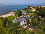 Set on over an acre of private Gold Coast beachfront, this 1927 Georgian estate is a masterclass in timeless grandeur and modern luxury. Meticulously renovated in 2024, the 4-bedroom, 7.5-bath residence features radiant heat on every level, custom Marvin windows and doors, and a state-of-the-art smart system with 36 audio zones. The heart of the homeâ€”a sun-drenched kitchen and family room with a 12-foot island and French doorsâ€”opens to sweeping water views. Seven custom fireplaces, original moldings, and marble finishes elevate every space. A 170-inch theater and three mini theaters redefine in-home entertainment, while the lower level dazzles with 12-foot window wells and shiplap ceilings. The stately primary suite offers panoramic Sound views, a heated balcony, and two custom walk-in closets. Outside, a heated pool, sauna, outdoor kitchen, and direct beach access create a private coastal paradise where elegance meets serenity.