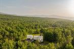 Welcome to Potter Mountain House, a masterfully reimagined Greek Revival church turned luxury designer estate. The original timber-framed structure was constructed in 1837 as the Manorkill Methodist Church, serving its community for over a century before being carefully dismantled and relocated to its current site in Gilboa, NY. Now sited on 37 acres with sweeping Catskill Mountain views, the building began its two-year transformation in 2023 by the boutique design/build firm ICDT Studio into a breathtaking 6, 242-square-foot residenceâ€”honoring its historic soul while layering in a refined, design-forward sensibility. The result is a one-of-a-kind architectural offering that balances reverence for the past with an intentional, contemporary design ethos.Inside, every detail delivers. The three finished levels are anchored by a soaring Great Room featuring the restored original timber frame, hand-hewn beams, and a full wall of windows that frame the panoramic mountain views. A round, sculptural gas fireplace adds warmth and ambiance between the living and dining spaces, while the chefâ€™s kitchen features a 48â€ AGA induction range, Fisher & Paykel appliances, Waterworks fixtures, and a stunning stone-clad island. A walk-in pantry accented by reclaimed wood beams and lined with Zellige tile completes the space. The spacious, open layout provides a striking balance of style and function for both daily living and entertaining.Ascending a symmetrical dual staircase, the Great Room opens into a dramatic library loft housed within the homeâ€™s original church cupola, crowned by an 18-foot long, multi-point glass chandelier and custom floor-to-ceiling bookcases. Just off the dining area, a glass-fronted, 625-bottle refrigerated wine room is enclosed by custom arched iron doors. The home offers five bedrooms and four-and-a-half exquisitely finished baths, each appointed with radiant heat, curated tilework, and an artful mix of stone and marble. The secluded primary suite occupies its own private wing and includes a spa-like bath with soaking tub, dual showers, Bardiglio marble, and double vanities framed by custom glass partitions. The walkout lower level features a secondary living room with wet bar, two guest quarters, built-in bunk room, and a spacious laundry suite with double washers and dryers. Lime-washed walls, wide-plank white oak flooring, and bespoke lighting carry a sense of quiet luxury throughout.Outside, multiple entertaining terraces and an expansive rear deck take full advantage of the natural surroundings, while a stream and seasonal waterfalls enhance the sense of tranquility. Additional features include an attached, heated, two-car garage, all-purpose mudroom, and a backyard master plan already prepared with plans for a future pool. Just 20 minutes from Windham Mountain Club, under an hour to Hudson and Albany, and a little over two hours from NYC, Potter Mountain House offers sanctuary, scale, and elevated design. A fully furnished option is also available, providing a true turnkey experience for effortless move-in. Unlike anything else on the marketâ€”distinctive, historic, and telling a story entirely its own.