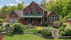 Tucked away on 20 peaceful acres in the scenic Town of Clinton, this distinctive contemporary retreat offers the rare combination of seclusion, style, and convenience. With the cachet of a Rhinebeck mailing address, inclusion in the Rhinebeck Central School District, and a location just minutes from Rhinebeck, Red Hook, and Millbrook, the property blends upscale country living with modern practicality.Perched on an elevated site across from Silver Lake, the home enjoys tranquil seasonal water views and a profound sense of privacy. Step inside to a wide, light-filled foyer that opens into the heart of the homeâ€”a dramatic living room with soaring vaulted ceilings, a striking floor-to-ceiling stone fireplace, and access to a generous rear deck overlooking the expansive, tree-framed backyard.Ideal for both entertaining and quiet moments, the main living area flows into a cozy den with French doorsâ€”perfect as a library, family room, or media space. The thoughtfully designed kitchen opens to a formal dining area, making dinner parties seamless. A nearby mudroom adds functionality with a half bath, laundry, storage, and direct access to the attached two-car garage.The main-level primary suite is a true sanctuary: spacious and serene, with dual walk-in closets and a spa-like en-suite bath that invites relaxation. Upstairs, two large bedrooms share a Jack-and-Jill bath, while an additional guest room or office has its own nearby full bath. A bright loft space, perfect for reading, working, or creative pursuits, overlooks the main living area and captures beautiful natural light through oversized windows.Rich hardwood floors and tasteful tilework add warmth and character throughout. On the finished lower level, you&rsquo;ll find an inviting media room, a wine cellar, a home gym complete with sauna, and another full bathâ€”offering exceptional flexibility for daily living and entertaining alike.Beyond the main house, a matching oversized detached garage is a standout feature. With two deep bays accommodating up to four vehicles eachâ€”including one with car liftsâ€”itâ€™s ideal for collectors, hobbyists, or future creative use. Above, a fully finished studio or office with cushioned flooring and climate control (heat AND AC) via mini-splits offers endless potential. A side-covered bay provides room for outdoor projects or additional equipment storage.Both structures are clad in durable Hardie-board siding and backed by propane-fired standby generators for year-round comfort and reliability.Whether you&rsquo;re hosting weekend guests, pursuing passions in the studio, or simply enjoying a quiet evening on the deck, this property offers a rare opportunity to live expansivelyâ€”with nature, luxury, and small-town charm in perfect balance.