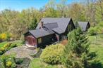 Tucked away on 7.26 acres of lush, storybook landscape with a stream-fed pond, this quintessential Woodstock home is more than a residenceâ€”itâ€™s an experience. As you approach via a winding driveway that crosses a babbling stream and year-round waterfalls, the magic begins. You can hear the cascading water from the house itself, setting the tone for the serenity that follows. The main home offers 2, 727 square feet of character-filled living space, while a charming 450 square foot guest cottage sits nearby, all nestled among vibrant mature gardens, handcrafted stone walls, and a gazebo. The tranquil, stream-fed pond at the heart of it all invites you to pause, breathe, and take it all in. Step inside to a soaring double-height great room with exposed beams and north-facing artistâ€™s windows that bathe the space in soft, natural light. A dramatic stone fireplace anchors the open-concept layout, creating an inviting flow between living and dining areas. The kitchen is a cookâ€™s dreamâ€”vaulted ceilings, skylights, custom wood cabinetry, artisan tilework, and a generous center island Need more space for entertaining? The sun-drenched sunroomâ€”with its skylight, terracotta floors, and cozy woodstoveâ€”is perfect for hosting guests or quiet nights in. French doors lead to a stone patio overlooking gardens that bloom in every season. A full bath with a steam shower on the main level offers additional convenience. The primary suite is a peaceful sanctuary with vaulted ceilings, garden views, a spa-like bath with soaking tub, and even a private outdoor shower beneath a fragrant trellis. Upstairs, a guest bedroom and full bath with skylight offer a retreat all their own. The surprises keep coming on the lower level: two large rooms with a full kitchen area, full bath, artistâ€™s studio, and cozy woodstoveâ€”ideal for creative work, extended guests, or a private home office. And then there&rsquo;s the guest house: a two-story jewel with its own deck above the stream, a vaulted upstairs bedroom with an expansive garden-facing balcony, and a warm, woodsy interior. Currently a permitted B&B, itâ€™s perfect for visitors and has an excellent rental income history. The fenced grounds are a true Edenâ€”carefully cultivated to deliver beauty all year long. Meandering lawns, specimen Japanese maples, weeping cherries, magnolias, evergreens, and a dazzling array of deer-resistant perennials create a living painting. Every step offers a new surprise, every corner a private nook. Modern upgrades add peace of mind, including a whole-house generator, new boiler, irrigation and security systems, new washer/dryer, and a newer roof. Just under five minutes to the center of Woodstock, and close to the trailheads of Overlook Mountain and Magic Meadow, this is a once-in-a-lifetime opportunity to own a private sanctuary that inspires creativity, joy, and rest.
