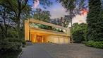 Welcome to a sanctuary in North Hills - a one-of-a-kind Frank Lloyd Wrightâ€“inspired contemporary masterpiece, creating a living space that feels both timeless and inviting. The home echoes Wrightâ€™s approach, using natural local material such as wood and stone, with strong horizontal lines and clean geometry. Wright also used windows and skylights to bring natural light deep into interiors and frame views of the landscape, and integrated art and custom designed elements throughout his homes, all elements incorporated throughout this home.Thoughtfully conceived by renowned architect Tim Maldonado, this 1.30-acre, 7, 200 +/- sqft estate in the village of North Hills offers a rare opportunity to experience refined luxury in a serene, private setting just minutes from New York City and the Hamptons. The 4 Bedroom, 7 bathroom residence was designed with complete privacy and artistic expression in mind. Clean lines, natural materials, and dramatic spatial relationships foster a fluid connection between indoors and out. Positioned along the primary street frontage and balanced by a sculptural cottage at the far end of the combined parcels, the estate becomes a secluded preserveâ€”an immersive sanctuary that celebrates sculpture, serenity, and modern luxury. Upon entry, the entrance features an elegant pair of intricately carved wooden doors imported from Paris. A sleek, modern sculpture stands to one side, contrasting beautifully with the natural elements. The overall design harmonizes traditional and contemporary styles, making the entrance both charming and sophisticated. The home is further distinguished with expansive flamed Canadian granite floors, while a striking water feature frames the floating steel staircase. The chefâ€™s kitchen is as functional as it is beautiful, featuring top-tier Miele, Subzero and Wolf appliances, bespoke European rift oak cabinetry, custom Ann Sacks tile, granite countertops, and a dedicated coffee station and pantry. Upstairs, the home continues to impress with a collection of serene, retreat-like bedrooms, two with its own en-suite bath, walls and ceilings finished in high-gloss lacquer for a refined, modern aesthetic. The primary suite is a private sanctuary, offering a spa-inspired bath with an oversized steam shower, multiple rain and body shower heads, a deep soaking tub, dual walk-in closets, and a private balcony overlooking the grounds. Nestled within lush, manicured grounds, the property offers an outdoor oasis, complete with a striking in-ground heated pool and spa, framed by mature fig trees, vibrant hydrangeas, a Koi pond, and expansive lounging and dining areasâ€”ideal for alfresco dining, entertaining and quiet relaxation. Adding to the estateâ€™s unique appeal is a separate, award-winning cottage known as â€œWaterfall Pavillionâ€ that received a Design Award of Merit from the Society of American Registered Architects (SARA) New York in the 2007 Design Awards. Designed with the warm, rustic charm of a mountain retreat, the pavilion features soaring ceilings with exposed beams, rich custom millwork, oversized windows with automated blinds, and refined finishes throughout creating a serene, Aspen-like atmosphere. The Pavillion includes a full kitchen outfitted with Wolf appliances, a luxurious spa-style bath, and a versatile flex space. No detail has been overlooked in the ongoing care and maintenance of the property. A heated three-car garage, finished lower level with kitchen, 1, 000 bottle count temperature-controlled wine cellar, updated five-zone central AC, reflective tinted glass windows, 2 commercial grade generators, and a durable rubberized roof all speak to the same level of thoughtfulness and quality that defines every inch of this remarkable home. This property is more than a residenceâ€”itâ€™s a work of art. A private sanctuary where contemporary design, nature, and luxury converge in one of Manhassetâ€™s most prestigious communities.