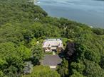 Introducing a truly exceptional waterfront estate nestled along the prestigious coast of Laurel Hollow, NY. Approached via a tree-lined driveway and set on 4.2 professionally landscaped acres, this Hamptons-style shingle and stone Colonial offers sweeping views of the glistening harbor from nearly every room and outdoor space. One of the homeâ€™s most distinctive features is its private mechanical tram - one of the only ones in the area - providing effortless access to a stunning Dock House with a kitchenette, just steps from your own sandy beach and deep-water dock.Originally constructed in 2004 and thoughtfully redesigned, this North Shore masterpiece features intricate hardwood floors, oversized windows, and a dramatic double-height entryway that sets the tone for the luxury within. Spanning three levels and serviced by a private elevator, the home offers 4 spacious bedrooms and 5.5 designer bathrooms.The open-concept layout is anchored by a striking bespoke bar with an illuminated countertop, alongside a gourmet center island kitchen equipped with chef-grade appliances and a walk-in pantry. Two impressive floor-to-ceiling fireplaces frame the dining and living areas, which extend to a full-length teak deck overlooking the meticulously landscaped grounds and tranquil shoreline. There is also a wet bar / built-in coffee station and a cozy den that provides a warm and inviting extension of the main living space.The Ownerâ€™s Wing is a luxurious retreat, accessed through double doors and featuring multiple walk-in closets, a spa-inspired ensuite bathroom, a fireplace, and French doors that open onto the second-story deck. Each additional bedroom includes its own ensuite bathroom. The first floor also offers a second den/flex space adjacent to a wet bar with a wine refrigerator, which leads directly to the outdoor entertaining area.Additional amenities include a 3-car attached garage with a car lift, a large laundry room with a convenient chute, and a finished lower level complete with a lounge space and a matted gym. Outdoor living is equally impressive, featuring an oversized covered bluestone patio, a heated in-ground pool, and an outdoor shower.This is a rare opportunity to own a one-of-a-kind coastal sanctuary that seamlessly blends luxury, privacy, and natural beauty in one of Long Islandâ€™s most coveted waterfront enclaves.