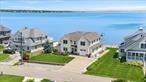 Experience the perfect blend of comfort, luxury, and waterfront living in East Quogue. Ideally located south of the highway in the desirable Shinnecock Shores community, this custom-built 2010 home offers breathtaking views of Shinnecock Bay & Ponquogue Bridge with exclusive beach rights, all just 82 miles from Manhattan. Spanning 3, 569 square feet on a manicured 0.26-acre lot, the cedar-shingled residence features 4+ spacious bedrooms, 4 bathrooms, and refined interior finishes throughout. The open-concept main level includes a welcoming entry foyer designed with a sightline to the open bay, a cozy den with gas fireplace and built-ins, and a living/dining area framed by Andersen windows showcasing uninterrupted bay views. A spacious kitchen is outfitted with GE Monogram stainless steel appliances, granite countertops, dual sinks, a 4-burner convection stovetop, wall oven and microwave, and a generous island with seating for four. The first-floor primary suite offers stunning water views, a walk-in closet, and a spa-like bath with a double vanity, walk-in shower with bench, and rainfall and handheld shower heads. Upstairs, a light-filled loft leads to three additional bedrooms -two with bay front balcony access-and a bonus room. Bathrooms feature double vanities, walk-in showers with rainfall showerheads, and linen closets. Outside, entertain from a waterside deck with a retractable awning, launch kayaks, or swim from the private, 70&rsquo; bulkhead with built-in ladder, and enjoy the convenient option of mooring your boat in Shinnecock Bay. This meticulously maintained home also includes modern mechanicals such as central HVAC - with separate controls in each bedroom, living room, family room, and den - natural gas fuel, central vacuum, full home security alarm and Ring camera systems, and property irrigation. Additional highlights include LED lighting, an interior sound system, Hunter Douglas custom window shades, a large first-floor laundry room, and partial 1/2 car garage for storage. The property benefits from low HOA dues and access to private community amenities, including a bay beach, private park, and snow removal. Don&rsquo;t miss this opportunity to live on the bay in style and comfort.