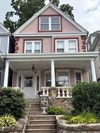 This single-family residence in East Yonkers features beautiful stucco on the exterior. The front porch, supported by elegant white pillars, offers a welcoming space to relax. The finished attic provides versatile extra living space.