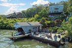 Set on the Western shore of Greenwood Lake, this terraced 4 bedroom, 2.5 bath home presents sprawling panoramic views of the lake and Sterling Forest. The layout invites light and vistas into nearly every room, blurring the boundary between interior space and nature. Step into a bright kitchen and follow shimmering water through the large open plan living/dining area to an expansive deck. On the upper level, three comfortable bedrooms offer additional views, generous closets and share a full bath with soaking tub + shower. The walk-out lower level features a self-contained suite with a private entrance, kitchenette, full bath, and utility room. The space is ideal for guests, extended family, or potential rental income. The outdoor areas invite you to enjoy lake living: rinse off in the outdoor shower, nap in the hammock, tend a terraced bonsai garden, or gather on the lakeside stone patio. A rare boathouse includes storage, bar seating and a lift for one boat while a cascading water feature provides ambience and completes the lakefront scene. Donâ€™t miss the rooftop solar panels (owned, installed 2015), attached one car garage, woodstove and central air for year-round comfort. Minutes to village shops, marinas, hiking trails and roughly an hour to New York City. This is lake life without compromiseâ€”where every day feels like vacation.