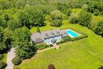 Welcome to this stunning colonial-style residence, beautifully situated on 6.26 acres in the scenic HudsonValley. This exceptional home greets you with a grand entrance, as pink cherry blossoms line thedriveway leading to a spacious three-car garage, while elegant Japanese Red Maples frame the street.Zoned for up to four horses, this private estate offers a perfect blend of charm and functionality. The in-ground pool, surrounded by view fencing, is ideal for relaxing and entertaining. Enjoy the serenity of alush, manicured lawn, vibrant gardens, and two brick patios, one featuring a full wood-burning fireplace.A full-length deck provides access to the interior and includes access to the half-bath for convenience.Inside, the home welcomes you with a graceful staircase, flanked by ornate arched entries leading into thelarge kitchen, seating/dining room and double French door entries into Grand Family Room withfireplace. Optional room can be used as guest bedroom/playroom or an office with French doors, perfectfor flexible use.The chefâ€™s kitchen is outfitted with solid cherry cabinetry, marble countertops, and stainless steelappliances, including a propane 5-burner island cooktop with seating for up to eight guests. A spaciousdining area flows into the Grand Family Room, showcasing 17-foot cathedral ceilings, wood-burningfireplace, arched features, double French doors and an abundance of natural light through multiple largewindows and skylights. Hardwood flooring flows throughout the main level.Additional main-level features include access to the garage, a half bath with washer/dryer hookups, anddirect entry to the rear deck.Upstairs, the primary suite is a luxurious retreat with soaring ceilings, custom arches, French doors, walk-in closets, and a spa-like bath with dual vanities, clawfoot soaking tub, walk-in shower, and private watercloset. Down the hall is an office with built-in bookshelves, a full bathroom, dedicated laundry room, utility nook with a sink and microwave, two additional bedrooms, and a second suite complete with fullbathroom.The fully finished basement includes 8 foot ceilings, a full bath and generous storage options.Located near a golf course, parks, top-rated schools, shopping, and fine dining, this extraordinaryproperty offers timeless elegance and modern convenience in one of the Hudson Valleyâ€™s most sought-after communities.