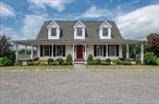 Set in the historic farming community of Ancram, this picture-perfect Cape sits gracefully on 20 pastoral acres surrounded by protected farmland. With timeless curb appeal, the home is complemented by a classic barn with two stalls and an oversized detached two-car garage, ideal for equestrian or hobby farm enthusiasts.A wraparound front porch evokes the charm of traditional farmhouse living, inviting you into a sun-filled interior where elongated windows and an open floor plan create a bright, airy atmosphere. The main level features a convenient first-floor en-suite bedroom just off the living room, perfect for ease of living.The thoughtfully designed mudroom with custom Crown Point built-ins and laundry facilities is accessible via a separate side entrance. Throughout the main level, contiguous hardwood floors offer a seamless sense of flow. The chefâ€™s kitchen is a standout, boasting quartz countertops, subway tile, and an open layout to the dining area, which leads to a serene screened porch overlooking open fields and rolling countryside.Upstairs, youâ€™ll find two additional bedrooms, a full bath, and a versatile loft space, great for a media room, office, or creative studio.Located near the beloved Ancramdale Loopâ€”one of Columbia Countyâ€™s most scenic biking trailsâ€”as well as hiking spots, cultural destinations, and charming rural hamlets, this is a special opportunity to embrace a peaceful and beautiful Hudson Valley lifestyle.