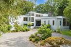 Welcome to this sleek, light-filled Contemporary in Armonk, where openness and design converge on 2.21 private acres in the award-winning Byram Hills school district. A circular driveway leads to a dramatic double-height foyer with gleaming marble floors, setting the tone for the sun-drenched interiors that follow.Walls of windows, soaring ceilings, and skylights flood the home with natural light. The expansive formal living room features a striking floor-to-ceiling stone fireplace and flows effortlessly into the spacious family room, dining area, and designer Leicht kitchen. A convenient home office is tucked just off the kitchen. Sliding doors open to a wraparound deck that seamlessly extends the living space outdoors, perfect for entertaining or relaxing in privacy.The private primary suite is a true retreat, complete with a balcony, two oversized walk-in closets, a dedicated shoe closet, and a generous dressing area. The spa-like bath offers a soaking tub and a freestanding shower.Upstairs, youâ€™ll find an en-suite bedroom plus two additional bedrooms that share a hall bath. The walkout lower level offers a vast, welcoming space with designated areas for recreation, fitness, media, and guests, plus a full bath, cedar closet, and abundant storage.With multiple fireplaces, flowing open spaces, and serene outdoor surroundings, this home offers a harmonious blend of contemporary design and everyday comfort.