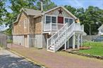 Set on two tax lots and bordered by preserved state land, this elevated 3-bedroom, 1-bathroom raised ranch is ideal for boaters, entertainers, or anyone seeking a relaxed coastal lifestyle. Raised by NY Rising and updated throughout, the home features 1, 194 sq ft of living space with a full-height basement offering incredible potential, accessible via double doors.Step into a vaulted foyer with chandelier and wood-burning stove that sets a warm, welcoming tone. The living area flows toward the rear of the home where you&rsquo;ll find a beautifully finished kitchen with granite countertops, a breakfast island with a hanging pot rack, stainless steel appliances, and glass-front cabinets.Hardwood floors run throughout, and the bathroom is elegantly done in tumbled marble. One of the secondary bedrooms features a custom loft with ladder access, adding extra functional space perfect for storage, a reading nook, or a play area.Outside, enjoy two raised Trex decks, a detached 2-car garage, a boat port, and freshly power-washed cedar shake siding. With DEC-permitted water access and docking potential at the rear, itâ€™s a dream setup for boaters. The home also includes brand-new central air, all-new plumbing, newer windows, a newer boiler, upgraded 200 AMP electric, and a newer roof, giving you peace of mind for years to come.Because the home has been elevated by NY Rising, flood insurance has been significantly reduced from several thousand dollars to just a few hundred annually. Low Taxes: $3, 968.69