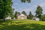 Step into a timeless masterpiece - an exceptional circa-1769 estate that remains a rare jewel of Hudson Valley history. Set across 96 pristine acres and graced with approximately 800 feet of serene stream frontage along the Mombaccus Creek, this remarkable property is a poetic fusion of colonial-era charm and pastoral tranquility. Experience an immediate sense of calm as you arrive along the beautifully paved, winding driveway, where picturesque views of the home, barn, and fenced pasture draw you in and invite further exploration. From the moment one enters, the home greets with elegant authenticity. A grand staircase stands at the heart of the space, accompanied by classic woodwork, hand-crafted built-ins, and wide plank flooring that whispers stories of centuries past. Expansive windows reveal sweeping views of the Mohonk Mountain House, offering an ever-changing canvas of natural beauty from nearly every room. The interior layout reflects its 18th-century origins while seamlessly supporting contemporary living. A cozy living room warmed by a wood-burning stove invites relaxation, while a dedicated entertainment space complete with a full bar promises memorable gatherings. The country-style kitchen blends rustic charm with modern sophistication, featuring top-tier appliances including a Wolf cooktop and oven, Miele oven and Sub-Zero refrigerator ideal for crafting gourmet meals with ease. Adjacent, the formal dining room highlights custom-built-in cabinetry and offers an inviting space for elegant entertaining and intimate gatherings. Transition seamlessly into the formal sitting room, complete with a cozy office nook perfect for working from home while enjoying sweeping views of the pastoral landscape beyond. Ascending the stairs, the second floor reveals three spacious bedrooms, two full bathrooms, and a versatile room perfect for an office, studio, or guest accommodation. A charming rear staircase tucked off the kitchen provides both a nostalgic touch and functional flow. Beneath the home, a full basement delivers ample storage and utility options, and a walk-up attic invites creative expansion. Beyond the walls, the grounds bloom in harmony with the changing seasons. Flowering trees and lush greenery frame every path and pasture. Be enchanted by the old covered bridge stretching over the babbling brook that winds its way behind the homestead. The estate also features a massive three-story barn and multiple outbuildings, allowing endless possibilities for farming, livestock, artisanal workshops, or imaginative pursuits. Spend time roaming the pastures, while enjoying the sound of the Mombaccus creek and taking advantage of the swimming holes on hot summer days. The location offers unparalleled access to the Hudson Valleyâ€™s finest destinations. Golf and upscale dining await at nearby Inness, while Arrowood Farms and Westwind Orchard serve up craft spirits and fresh fare. Local favorites like Mill & Main Provisions, Flying Goose Tavern, and Rough Cut Brewery bring culinary creativity to the neighborhood. Saunderskill and Kelderâ€™s Farms offer seasonal bounty and berry picking come autumn, while Minnewaska State Park presents miles of scenic trails for hiking and biking adventures. Situated just 90 minutes from Metro New York, this property delivers a once-in-a-lifetime opportunity to own a living piece of early American history. Embrace the chance to become the fourth steward of this generational farmstead nestled in the heart of the breathtaking Hudson Valley.
