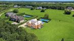 Dare to dream across nearly 19 acres in Water Mill North, where architecture, nature, and lifestyle align to create a truly rare estate. Set along a private access road, the new construction residence provides resort-style living masterfully crafted by a premier Hamptons builder and refined by the award-winning Manhattan design firm, A-List Interiors. This unique offering includes full ownership of a protected agricultural reserve, serving as the estateâ€™s expansive backyard for your personal enjoyment. Whether you envision wildflower fields, orchards, open terrain for horses, or a private vineyard, the expansive land offers an extraordinary canvas for your aspirations. Bespoke finishes and thoughtful design offer gracious and balanced spaces for gathering and serenity over 10, 000 square feet across three finished levels, connected by a private elevator. A double-height foyer with expert millwork welcomes guests into the eight bedroom, ten full and two half bathroom home. The first floor offers a powder room with floating marble vanity, a formal dining room, great room with architectural oak ceiling beams, double-sided gas fireplace, den, and luxurious bedroom ensuite with soaking tub, dual vanities, a walk-in closet, and radiant heat floors. The custom white oak kitchen features elevated details, including a spacious center island, curated natural stone countertops, integrated Sub-Zero refrigerator and freezer with center glass wine column, Wolf range, beverage drawers, breakfast bar, and an elegant butlerâ€™s pantry with tailored inset metal accents. A mudroom, full cabana bathroom, laundry room and secure package room for seamless deliveries round out the first floor with grace and function. Relax in the second-floor primary bedroom suite with a soaring cathedral ceiling, linear fireplace, dual walk-in closets, and a spa bath wrapped in striking Arabescato marble. Radiant heat floors, a soaking tub, double vanities, and a glass-enclosed shower create a sense of everyday escape. This floor offers four additional guest bedrooms, all with ensuite baths, walk-in closets, and a shared terrace with outdoor fireplace, offering enchanting views over the reserve and perfect for cozy evenings beneath the stars. The fully finished lower level, with eleven-foot-high ceilings, reflects the elegance woven throughout the home and offers space for your favorite rejuvenation and entertainment activities. This retreat includes a golf simulator, state-of-the-art theater, a cedar-lined dry sauna and steam shower. A large recreation area, two ensuite guest bedrooms, and a sleek wet bar with lounge offer ample space for hosting or relaxing in privacy. A glass-walled gym opens to a peaceful outdoor wellness retreat complete with cold plunge, tranquil water feature, and a dedicated yoga or meditation terrace with walkout egress to the private backyard oasis. Outdoors, lounge in the sunny backyard by the 20-by-50-foot heated saltwater gunite pool and spa or take refuge in the shade under the pergola or one of the covered bluestone patios. The outdoor fireplace and built-in barbecue make for easy indoor/outdoor entertaining, as well as the convenient outdoor shower. Steps beyond the pool, enjoy spirited matches on the north/south-facing all-weather tennis court. As the recreation area extends to the reserve, the dreamscape to pursue new interests or lifelong passions adds a whole new dimension to this remarkable lifestyle. For budding vintners, the opportunity to cultivate a boutique private-label vintage is mere steps away. Equestrians will see the hallmarks of Hamptons horse country in the flat open grounds with potential for riding trails, arenas, and paddocks. More than an impressive estate, this home offers space to breathe and to define your own version of what it means to live well. Completion of the residence is scheduled for Winter 2026.