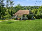 Fall in love with this newly renovated and modernized cottage on nearly 1 acre of private property. The sun-filled, open-concept floor plan features brand-new flooring, a stunning kitchen, wood-burning fireplace, and vaulted ceilings. Enjoy mountain views and Lake Carmel in the distance from the large bay window. The first-floor primary bedroom includes sliding doors with a Juliet balcony and a full bathroom nearby. The lower level offers a den/office, laundry, and storage with a separate entrance. Relax on the front porch or entertain in the spacious backyard with a stone patio and firepit. A large shed and attic provide ample storage. Major recent upgrades include a 200-amp electric panel, new HVAC, sump pump, water heater, and septic tank. Prime commuter location near highways, Metro-North, and shopping. Lake rights to beautiful Lake Carmel for beach access, swimming, boating and fishing! Close to state parks, Centennial Golf Club, and Thunder Ridge Ski Area.