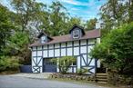 A Charming Country Retreat in exclusive Tuxedo Park. Set on a street among some of the most gorgeous estates in the area, this home, built as a carriage house in 1900, is nestled on a natrually landscaped 0.58-acre lot. The outdoor space is just as inviting, featuring a brick patio, moss-covered boulders, and a stone wall-lined property that provides a serene, private setting.The 2, 518 sq. ft. of living space offers a flexible layout to suit your lifestyle. The first floor features a spacious living room with a fireplace, a state-of-the-art kitchen, and an open dining room. A versatile bedroom on this level can easily function as an office, studio, or family room, and includes a full bathroom with a steam shower. A convenient laundry room and mudroom complete the floor.Upstairs, the primary bedroom is a private sanctuary with a full bath, a walk-in cedar closet, and a private terrace. The second floor also features a flexible den that can serve as an additional office or hobby room, plus two more bedrooms and another full bathroom.This beloved property has been meticulously maintained, with recent updates including a new roof, fresh paint, updated utilities, and new kitchen appliances. Combining historic charm with a functional, flexible floor plan, this home is a perfect country sanctuary.