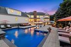 Opulence and grandeur define this 9, 355 +/- sf. custom-built estate in the prestigious North Harbor section of Miller Place. Perfectly sited on .92 acres of exquisitely landscaped grounds, this residence offers an unmatched lifestyle, where architectural detail, thoughtful design, and expansive spaces for entertaining come together in perfect harmony. Every element has been curated with intention, leaving an unforgettable impression at 2 N Harbor Down. A sweeping front porch framed by lush landscaping sets the stage, while a custom cast iron entry door opens to a dramatic foyer with soaring 20-foot ceilings, a crystal chandelier, and a grand staircase. Natural light pours into the great room, where coffered ceilings, raised panel molding, built in speakers throughout and a gas fireplace create an inviting yet refined atmosphere. The chefâ€™s kitchen is a masterpiece, featuring a large dining space, additional seating area with tv, solid white custom cabinetry, granite countertops, porcelain tile floors, and top-of-the-line appliances: Sub-Zero refrigeration, Wolf double convection ovens, a 36â€ induction cooktop, dual sinks, and a built-in Miele coffee system with filtration. A butlerâ€™s pantry with illuminated china cabinetry, wine refrigerator, and granite surfaces seamlessly connects to the formal dining room, setting the stage for exceptional entertaining. The main floor includes a private office with custom built-ins, two powder rooms, laundry room and three car garage with both interior and basement access. The first-floor master suite is a true retreat, offering a private sitting area, french doors leading to the expansive deck, a bespoke walk-in closet with quartz surfaces, and jewelry trays. Enjoy the spa-inspired bathroom with heated marble floors, jetted soaking tub, double vanities, and a custom walk-in shower with temperature control. The impressive second floorâ€™s cat walk overlooks the grand living room & foyer, setting the tone for luxury. A built-in bookshelf with a sitting area is the perfect place to escape and read your favorite book. Next up is the master suite with a private sitting area, beverage station, a custom walk-in closet with quartz finishes and a spa bathroom echoing the luxury of the first. Two additional guest bedrooms both with walk-in closets, custom cabinetry, and a shared spa like Jack & Jill bathroom. The spacious bonus room over the three car garage has endless possibilities connected to a service staircase to the kitchen below. The finished lower level was designed for entertainment and wellness, featuring a cozy living area with a Lexington Forge fireplace, wine refrigerators, a full entertainment kitchen equipped with an ice maker, dishwasher and sitting area. Enjoy a game of pool in the billiards room or get in a workout or massage at the end of your day. The lower level is also outfitted with a large cedar closet, multiple storage rooms, powder room two staircases and utility room. The backyard is an entertainerâ€™s paradise starting with the upper deck overlooking the grounds. An in-ground heated saltwater pool with sun deck and waterfall is surrounded by an expansive Technoblock patio, slate coping with multiple seating areas, and accent lighting. A fully equipped outdoor kitchen includes a Coyote grill and sink, turbo grill, refrigeration, and quartz counters, ideal for al fresco dining. The firepit area is the perfect place to gather around and relax. Custom lighting, lush landscaping, fountain and outdoor speakers elevate the experience. Just minutes from Cedar Beach, this custom-built residence represents the pinnacle of North Shore living. Designed by its original owners with a focus on style, comfort, and sophistication, 2 N Harbor Down is a rare opportunity to experience a home that truly has it all.