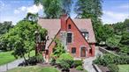 Step into this charming 1930 Tudor-style home in the heart of Poughkeepsie, where timeless character meets generous living space. A bluestone front patio welcomes you into a grand entry foyer, leading to a formal living room, cozy den, oversized dining room, half bath, and an eat-in kitchen. Just off the kitchen, an expansive deck overlooks the private, beautifully landscaped corner lot.The second floor features a spacious bedroom with en-suite bath and original fireplace, a bright guest bedroom with Juliet balcony, and a primary suite complete with en-suite bath, his-and-hers closets, and linen closet. Despite its vintage, this home offers unusually large bedrooms and ample storage space.Ascend to the finished third floor to find two additional bedrooms, a full bath, and unfinished storage space â€” all highlighted by original hardwood floors that continue throughout the home.The ground level includes a two-car garage with access to a finished basement offering extra living space and a half bath. Two interior staircases connect the main and second floors, adding to the home&rsquo;s unique charm.Brimming with original details and centrally located to shopping, dining, schools, and transportation, this timeless Tudor is ready for its next owner to make it their own.